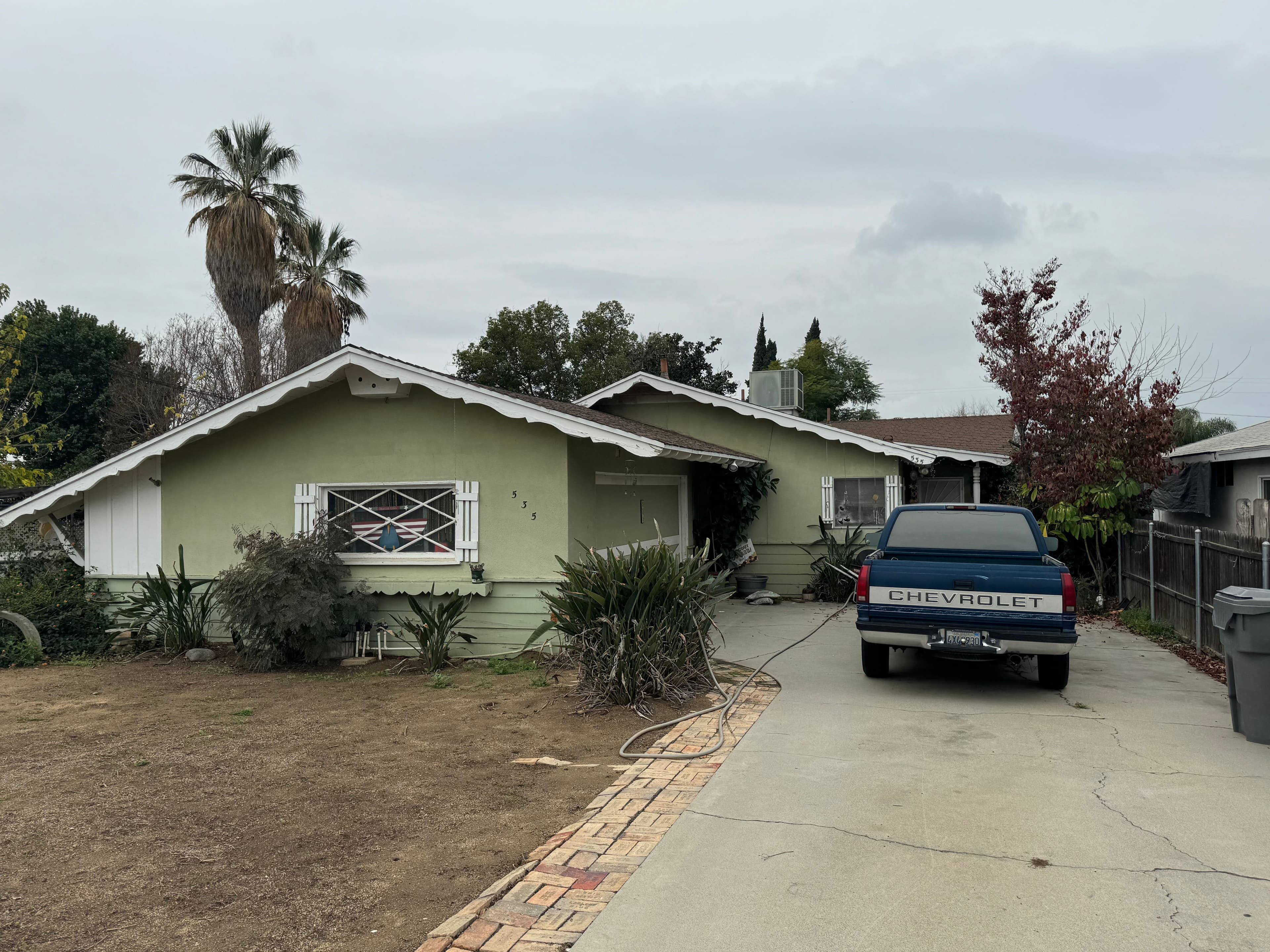 Run-down California home mid-renovation with a ladder and contractor truck in the yard